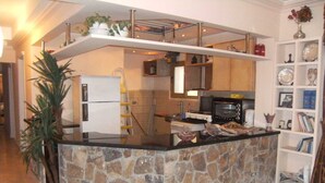 A kitchen with a stone island, a refrigerator, a stove, and a microwave. - Central 3BR Flat in Most Classy Spot in Mohandseen (Giza Governorate)