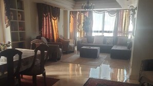A spacious living room with a dining area, a sofa set, and a chandelier. - Central 3BR Flat in Most Classy Spot in Mohandseen (Giza Governorate)