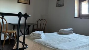 A hotel room with a bed, a chair, a small table, and a window. - Tower mini suite in historic farmhouse steps from lake beach (Lazio)