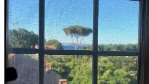 A window with a view of a tree and a building. - Tower mini suite in historic farmhouse steps from lake beach (Lazio)
