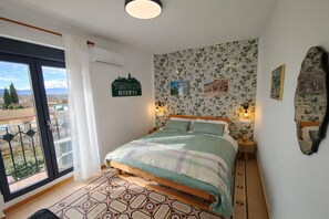 Una camera da letto con un letto, un comodino, una sveglia a parete, una finestra con vista e un cartello sul muro.