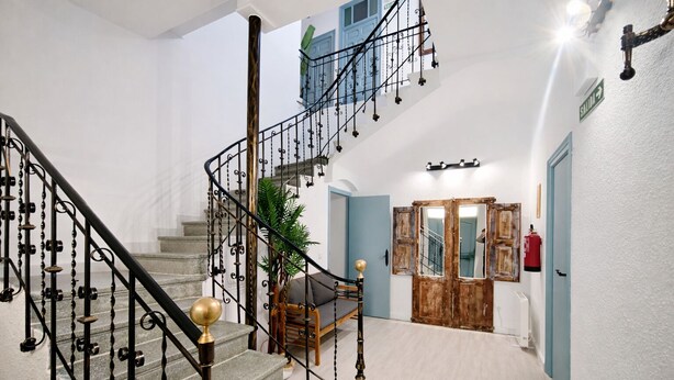 A staircase with ornate metal railings and a wooden chair.