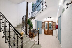 Una scala con ringhiere in metallo decorate e una sedia in legno.
