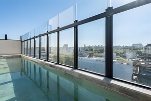 Ein Dachpool mit großen Fenstern und Blick auf die Stadt.