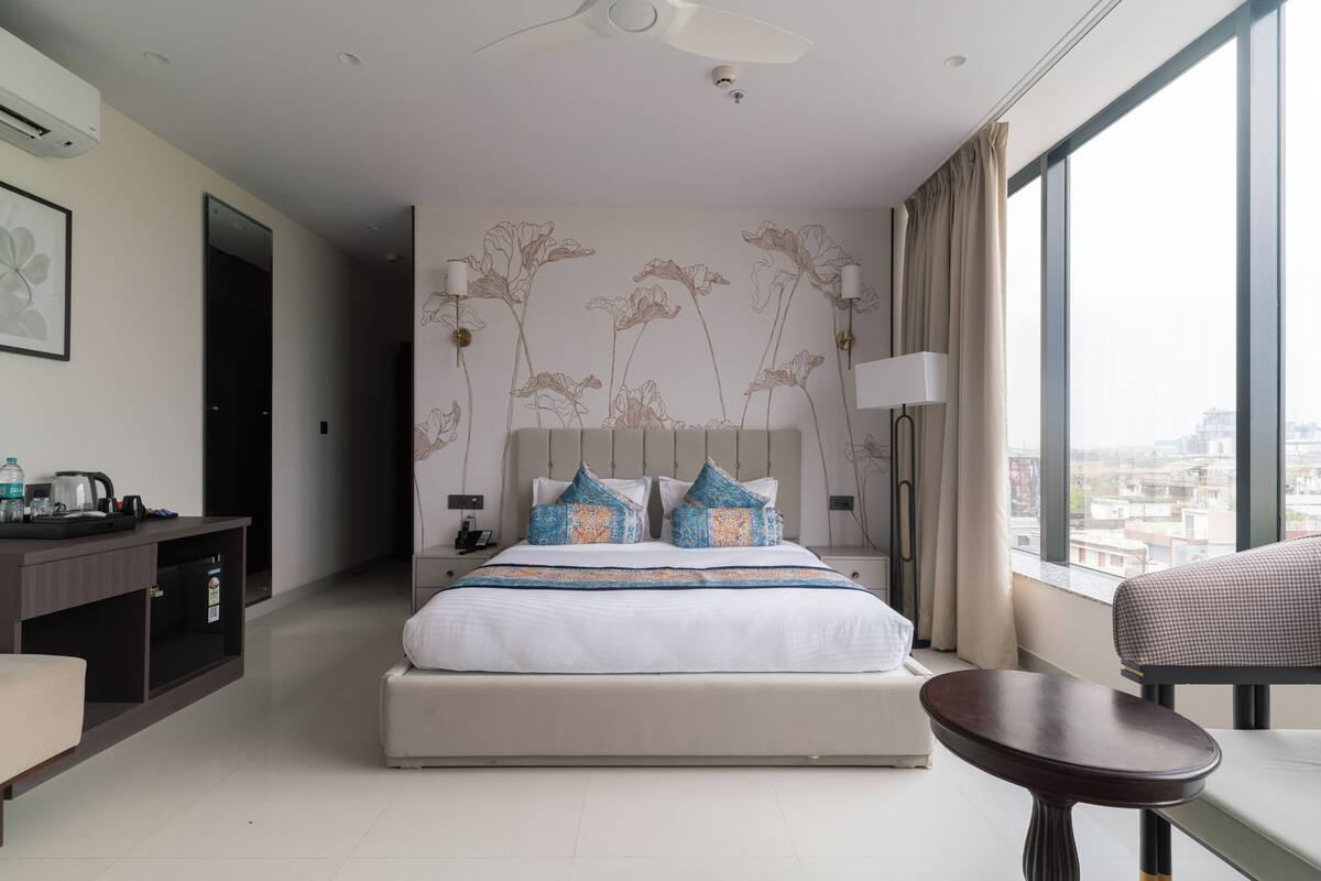 Una habitación de hotel moderna con una cama grande, un escritorio, una silla y vistas a la ciudad.