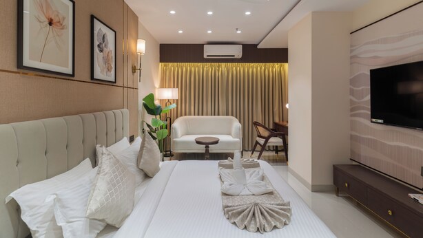 Una habitación de hotel con cama, sofá, televisión y ventilador de techo.