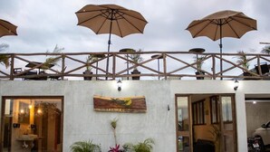 A building with a wooden deck, umbrellas, and potted plants.