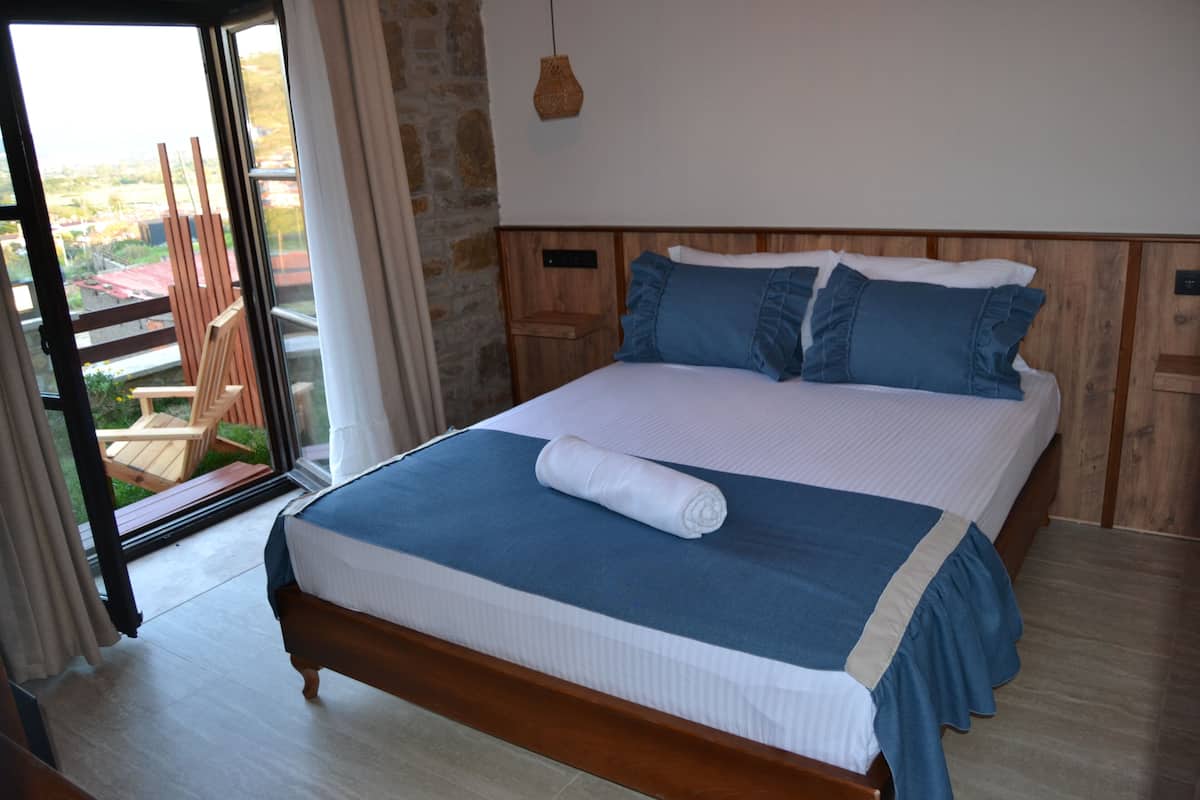 A bedroom with a bed, a window, and a view of the outside.