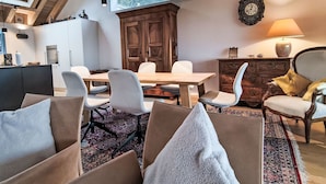 Een eetruimte met een houten tafel, stoelen, een grote kast en een klok aan de muur.
