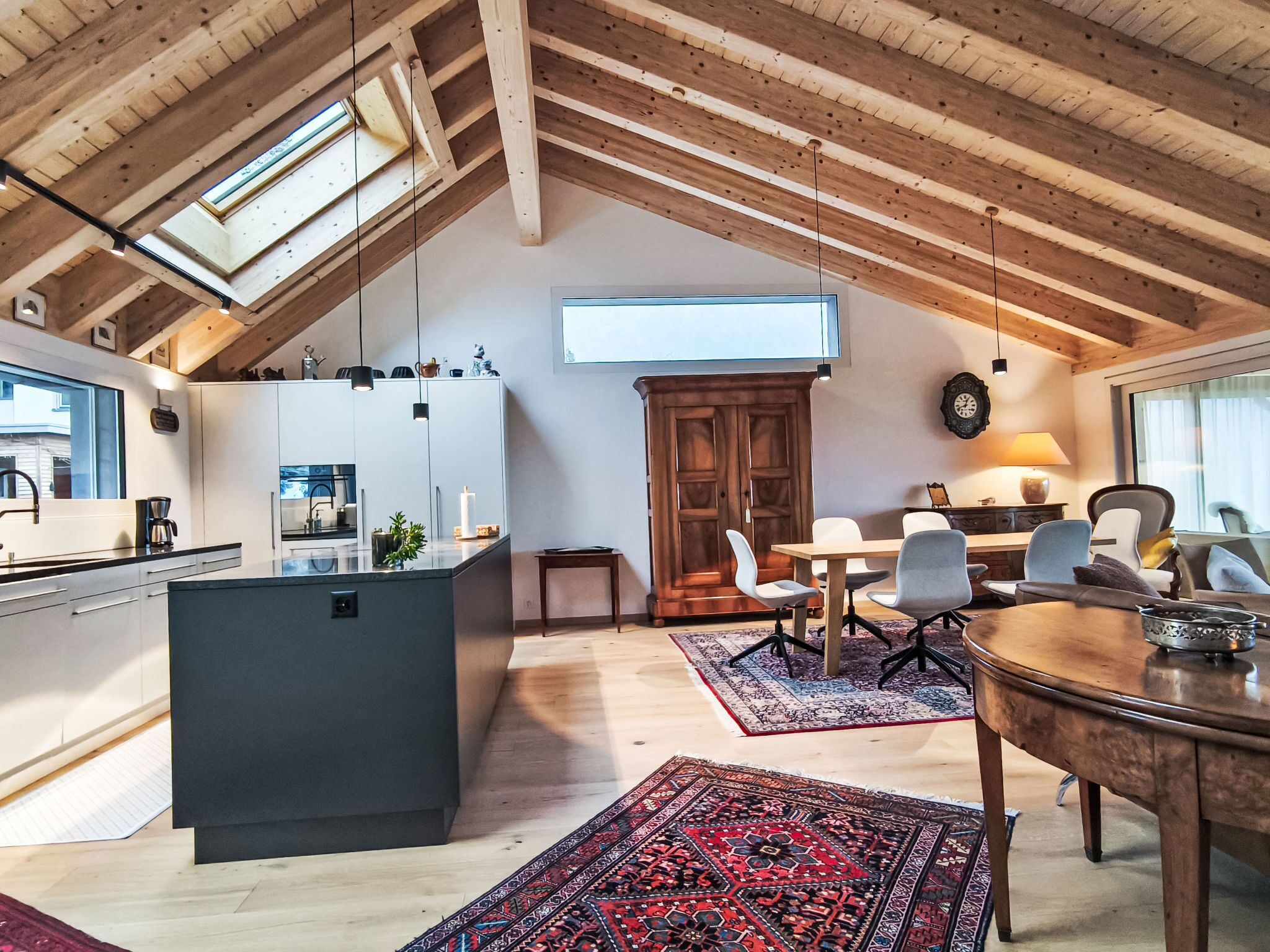 Ein großzügiges Loft mit hoher Decke, Dachfenster, moderner Küche, Essbereich und einer gemütlichen Sitzecke.