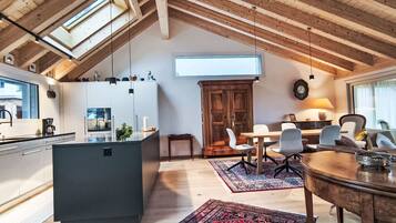 Ein großzügiges Loft mit hoher Decke, Dachfenster, moderner Küche, Essbereich und einer gemütlichen Sitzecke.