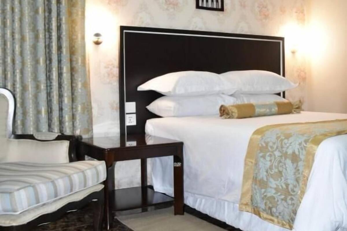 Un dormitorio con una cama, una silla, un equipo de aire acondicionado y un aplique de pared.