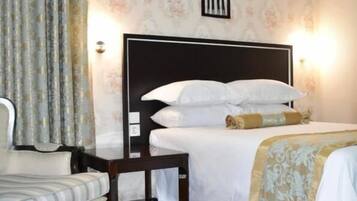 Un dormitorio con una cama, una silla, un equipo de aire acondicionado y un aplique de pared.