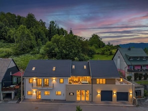 Ein modernes, zweistöckiges Haus mit Balkon, Garage und einer gut beleuchteten Eingangsparte.