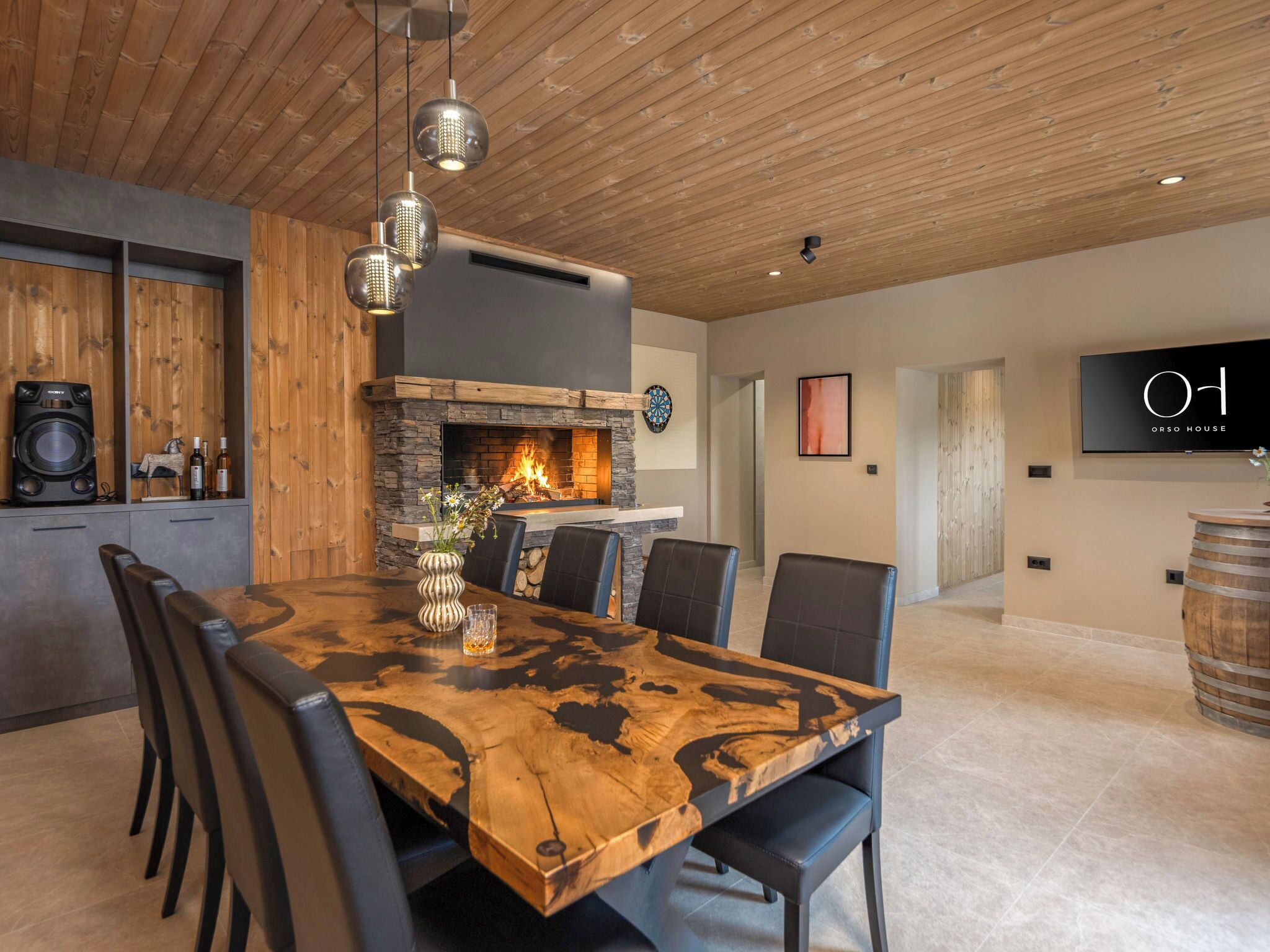 A dining area with a large wooden table, black chairs, and a fireplace.