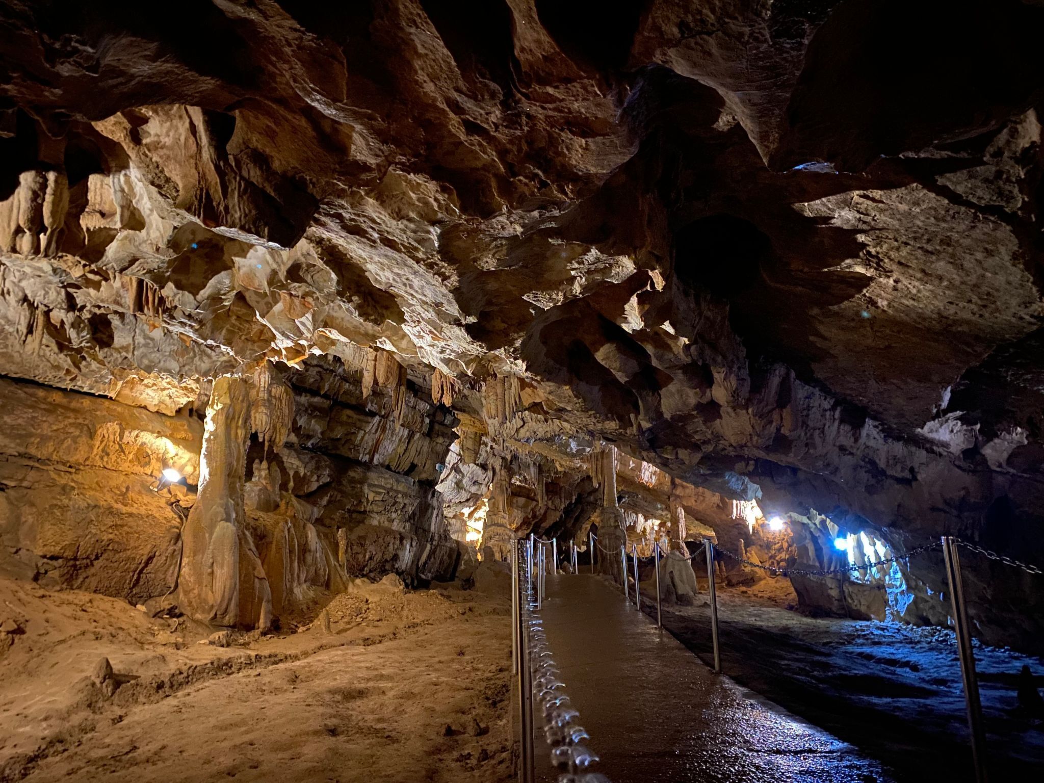 Una cueva con estalactitas y estalagmitas, un pasillo y cadenas de seguridad.