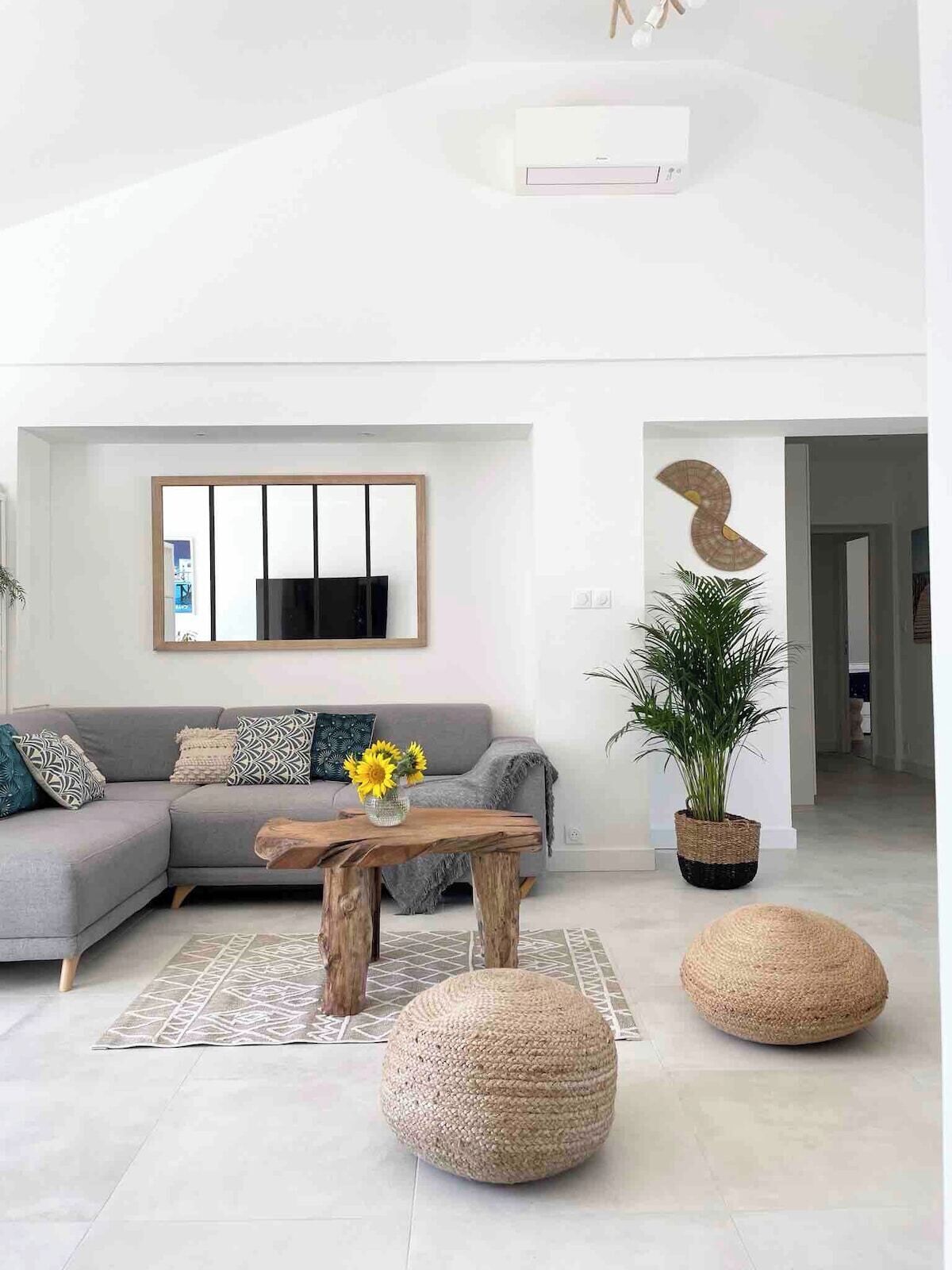 A modern living room with a grey sofa, a wooden coffee table, and a large potted plant.