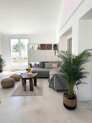 A modern living room with a sofa, coffee table, and potted plants.