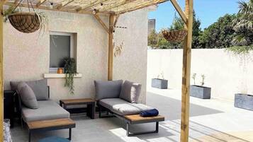 An outdoor seating area with a pergola, cushioned seating, and planters.