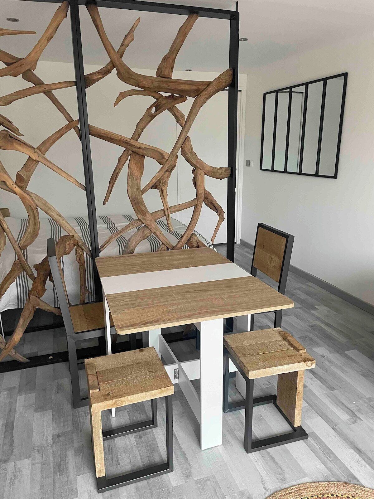 A modern dining area with a wooden table and chairs, a decorative wall with abstract patterns, and a framed artwork on the wall.