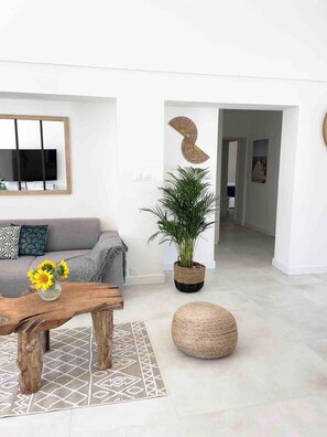 Ein modernes Wohnzimmer mit einer Couch, einem Couchtisch mit Sonnenblumen, einer Topfpflanze und einem runden Hocker.