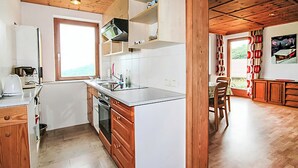 A modern kitchen with wooden beams, a large window, and a dining area with a view.