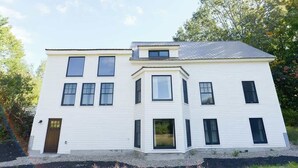 Een herenhuis met twee verdiepingen, een centrale ingang, meerdere ramen en een schuin dak.