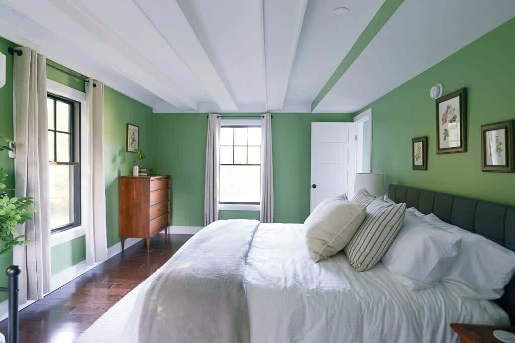 Une chambre à coucher avec un lit, une commode, une porte et une fenêtre.