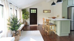 Een moderne keuken met een centraal eiland, houten stoelen, een bank en een potplant.