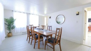 A dining area with a wooden table and chairs, a potted plant, and a round mirror on the wall.