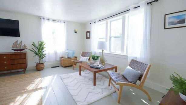 A living room with a sofa, a coffee table, a TV, a fireplace, and a window with curtains.