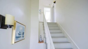 A staircase with white railings and steps, a framed picture on the wall, and a small shelf with a decorative item.
