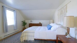 A bedroom with a bed, bedside table, lamp, and a window with curtains.