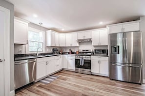 Una cocina moderna con armarios blancos, electrodomésticos de acero inoxidable y piso de madera.