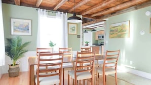Een eetgedeelte met een houten tafel en stoelen, een potplant en kunst aan de muren.
