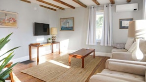Een woonkamer met houten balken, een televisie, een bank, een salontafel en een vloerkleed.