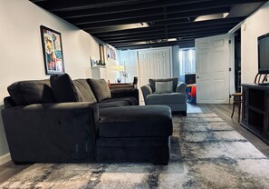 Ein Wohnzimmer mit Ecksofa, einem zusätzlichen Sofa, einem Teppich und einem Fernseher.
