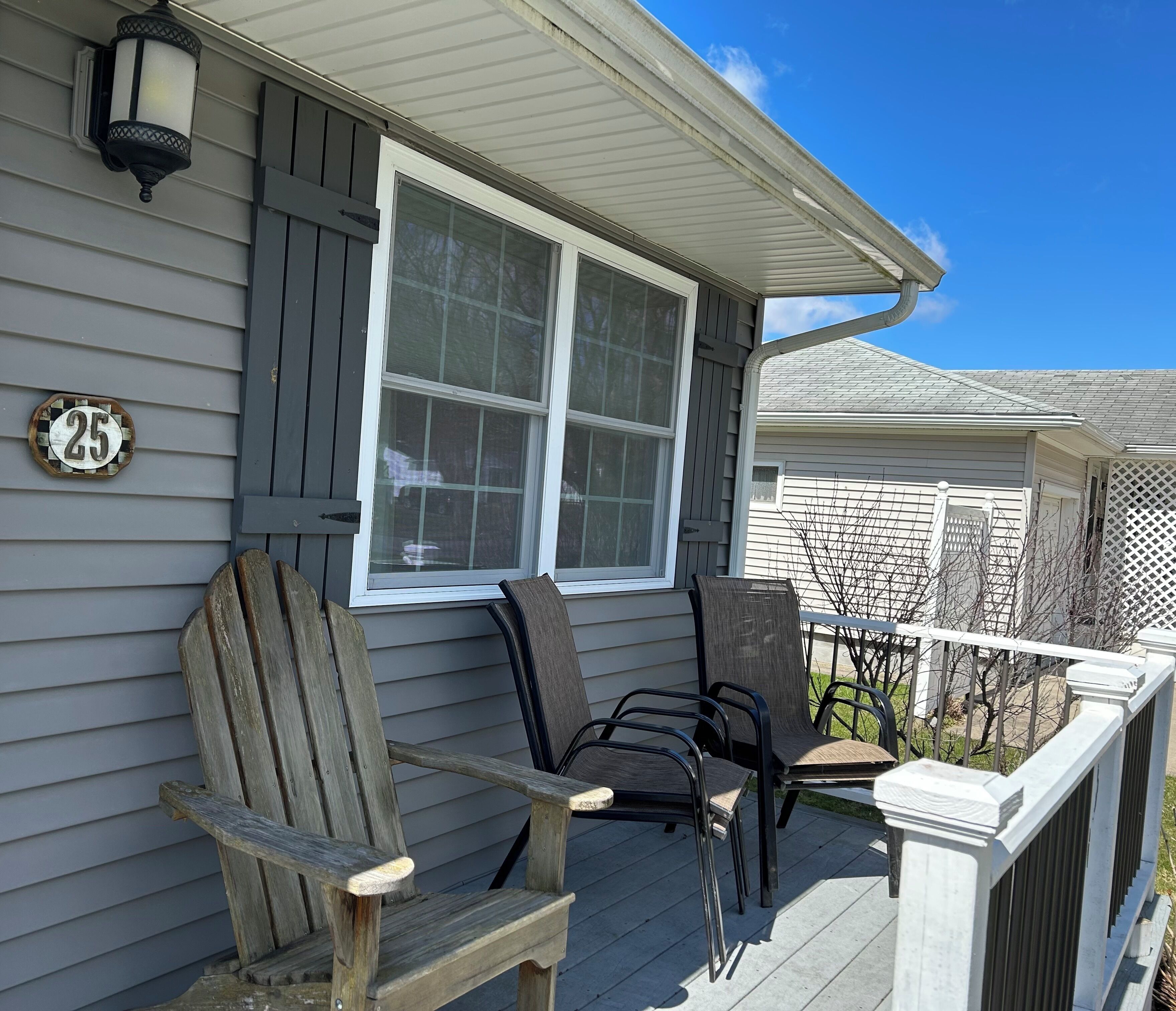 A house with a porch, two Adirondack chairs, a window, and a number 25 sign.