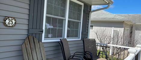 A house with a porch, two Adirondack chairs, a window, and a number 25 sign.