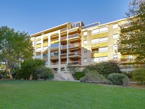 A multi-story residential building with balconies, a central staircase, and a well-maintained lawn. - Les Regates by Interhome (Hyères)
