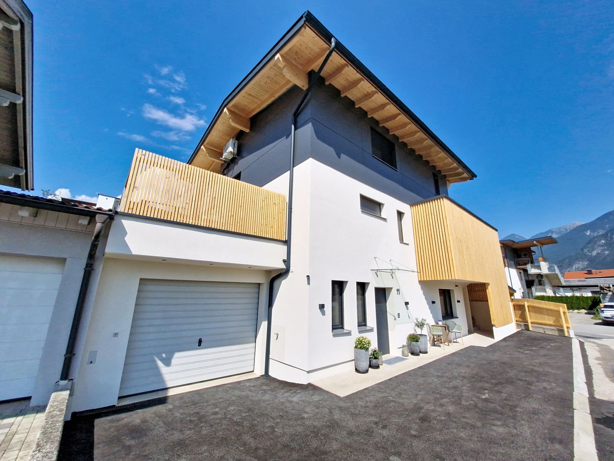 Une maison moderne à deux étages, dotée d’un garage, d’un balcon et d’une allée.
