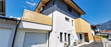 Une maison moderne à deux étages, dotée d’un garage, d’un balcon et d’une allée.