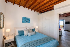 A bedroom with a bed, nightstands, a wardrobe, and a view of the outside. - Tzados Sunny Villa - Tinos Summer Retreat (Tzados)