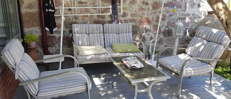 A patio with striped furniture, a table, and a statue.