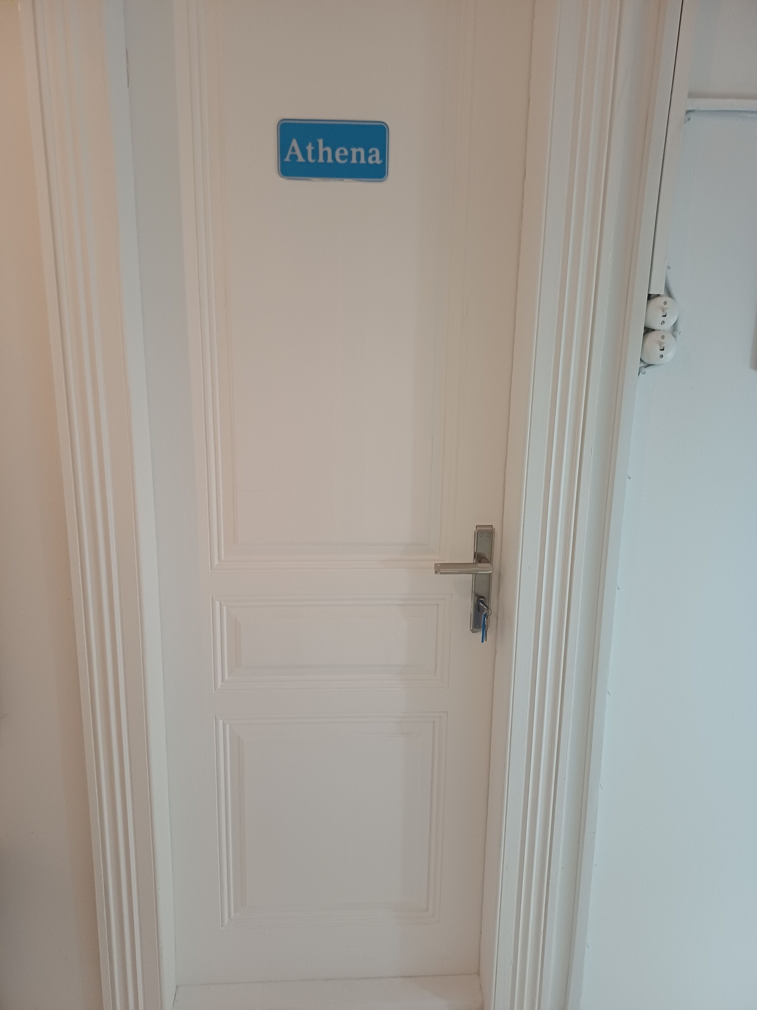 Una puerta blanca con un letrero que dice 'Athena'.