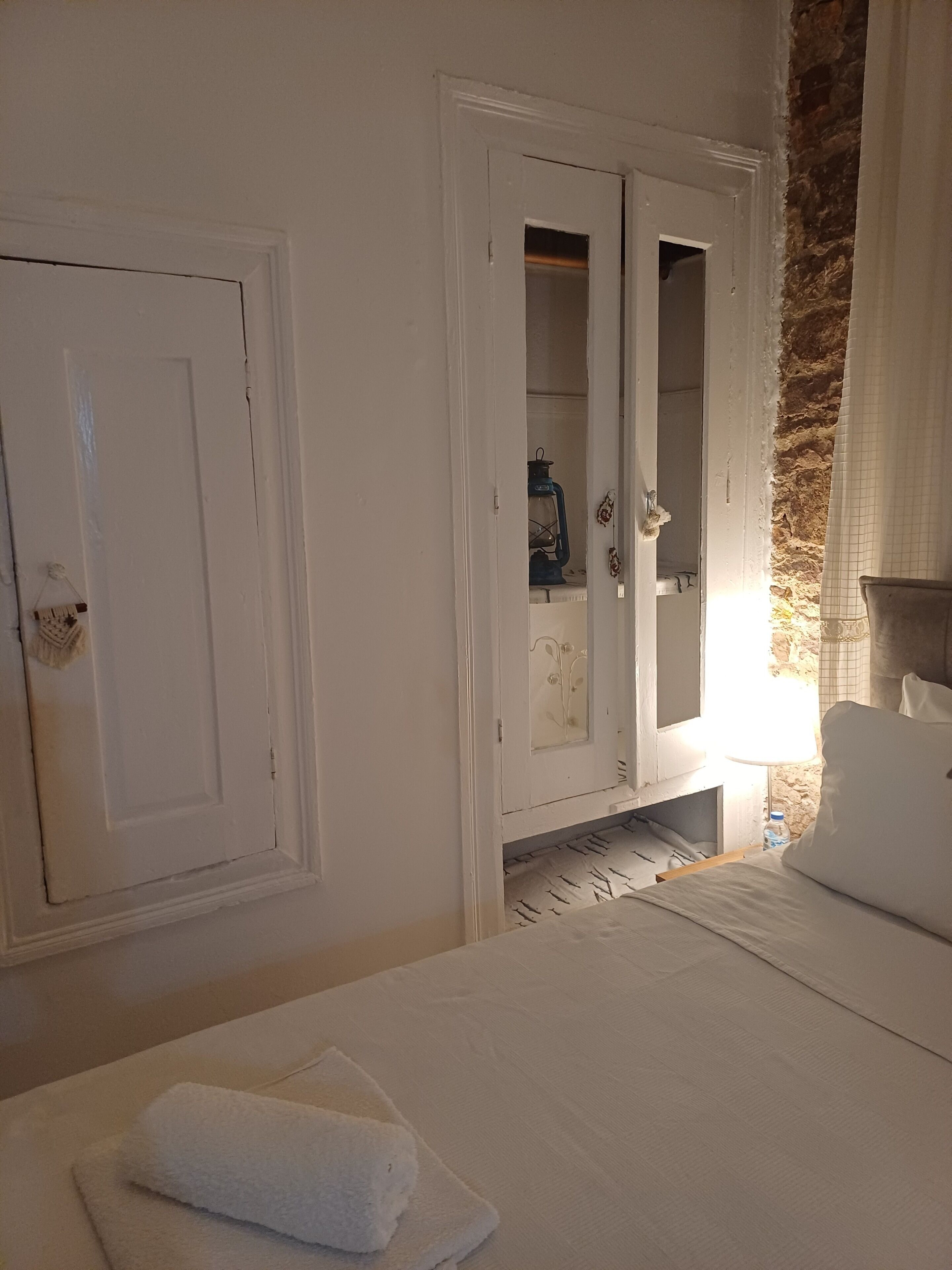 A hotel room with a bed, a wardrobe, and a bathroom visible through an open door.