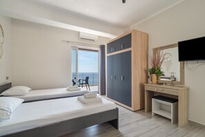 A bedroom with two beds, a desk, a TV, and a balcony with a view. - Intimate Sea View Studio for Two in Kefalonia (Vlachata)