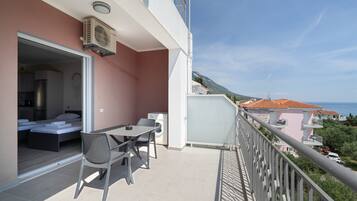 A balcony with a table and chairs, a washing machine, and a bed in the adjacent room.