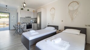 Una moderna camera d'albergo con due letti, angolo cottura, zona pranzo e balcone.