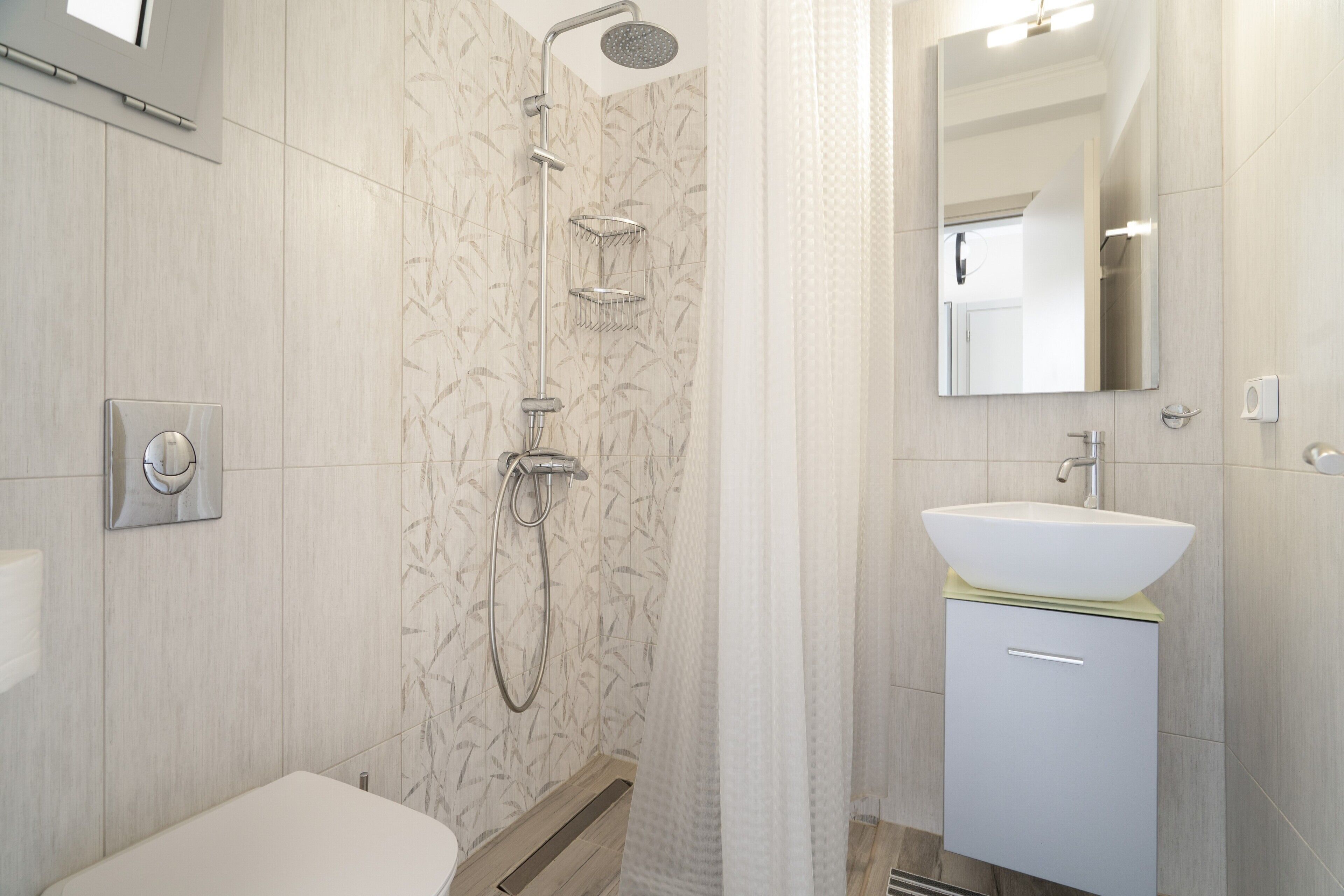 Une salle de bain moderne équipée d’une douche, de toilettes, d’un lavabo et d’un miroir.